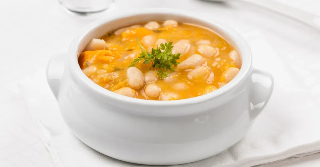 A pot of simmering Sopa de Pollo on the stove, with tender chicken and vegetables cooking in a rich broth.